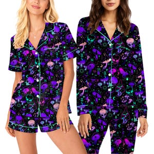 Peut inclure: Ensemble de pyjama noir avec un motif vibrant de champignons violets, de t&ecirc;tes d'extraterrestres et de symboles c&eacute;lestes. L'ensemble comprend une chemise boutonn&eacute;e &agrave; manches courtes et un short, bord&eacute;s d'un passepoil vert clair. Le tissu a un aspect doux et confortable.