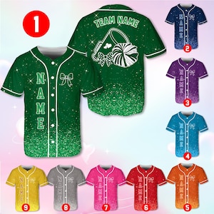 Op de afbeelding: Een verzameling honkbalshirts in verschillende kleuren, waaronder groen, blauw, paars en oranje. Elk shirt heeft een strik-afbeelding en het woord "NAME" verticaal op de voorkant. De achterkant van het groene shirt toont "TEAM NAME" en een pompon-ontwerp.