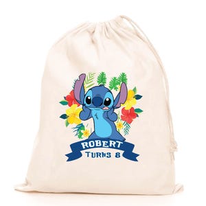 May include: A cream-colored drawstring bag featuring a graphic of the blue character Stitch surrounded by colorful tropical flowers and green leaves. Below the character, a dark blue banner displays the text ROBERT TURNS 8 in white letters.