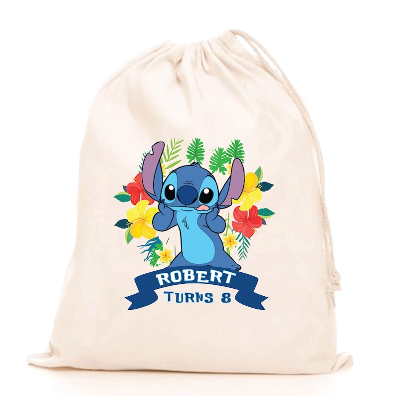 May include: A cream-colored drawstring bag featuring a graphic of the blue character Stitch surrounded by colorful tropical flowers and green leaves. Below the character, a dark blue banner displays the text ROBERT TURNS 8 in white letters.