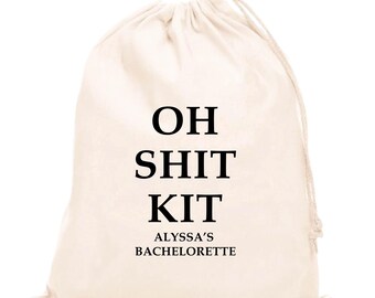 May include: A cream-colored drawstring bag with the words "OH SHIT KIT" in bold black letters. Below, in smaller text, it reads "ALYSSA'S BACHELORETTE". The bag is made of a soft, natural fabric.