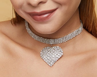 May include: A silver choker necklace with a large heart-shaped pendant covered in clear rhinestones.