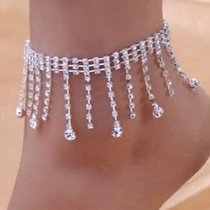 May include: Silver ankle bracelet with a fringe of dangling rhinestones.