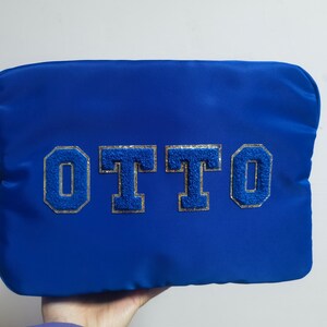 May include: A blue zippered pouch with the name "OTTO" in silver and blue glitter letters.
