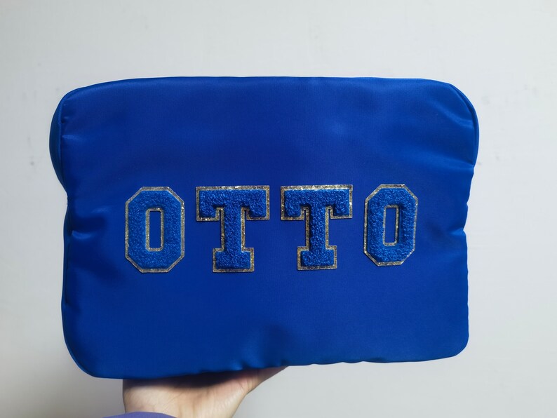 May include: A blue zippered pouch with the name "OTTO" in silver and blue glitter letters.