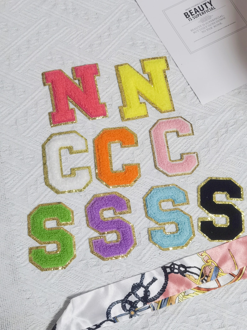 May include: A set of felt letters in various colors, including pink, yellow, white, orange, light blue, purple, green, and black. The letters spell out "NNCCSSS".