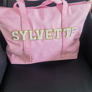 May include: A pink tote bag with a white and gold "SYLVETTE" design.