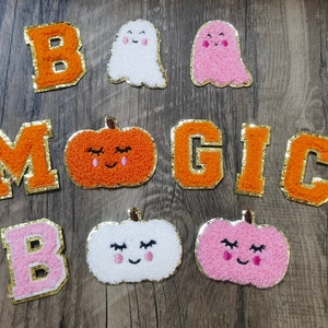 May include: A set of felt patches with the words "Boo Magic" and images of pumpkins and ghosts. The patches are orange, pink and white.