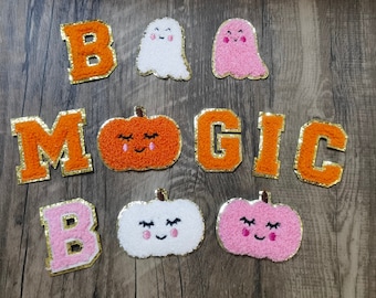 May include: A set of felt patches with the words "Boo Magic" and images of pumpkins and ghosts. The patches are orange, pink, and white.