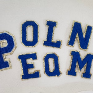 May include: Blue felt letters with gold trim spelling out the word "POLN EQM".