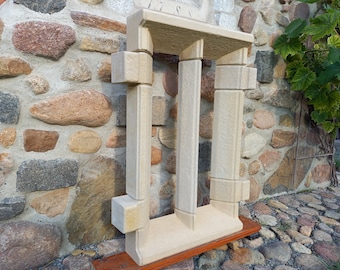 May include: A white stone archway with three pillars, resembling a miniature version of a classical building. The archway is displayed on a wooden base.