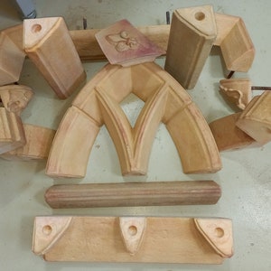 May include: A set of 10 wooden molds for creating a decorative archway. The molds are made of light brown wood and have a smooth, polished finish. The molds are arranged in a circle on a light brown surface.