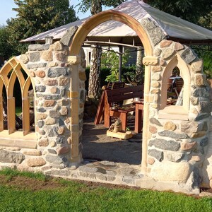 May include: A stone archway with a wooden frame and a stone wall on either side. The archway is made of rough-hewn stones and has a rustic look. The wall is made of smaller stones and has a more polished look.