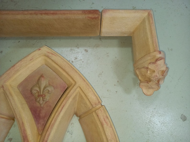 May include: A set of decorative architectural moldings made of plaster or stone. The moldings feature a fleur-de-lis design and are painted in shades of beige and brown.
