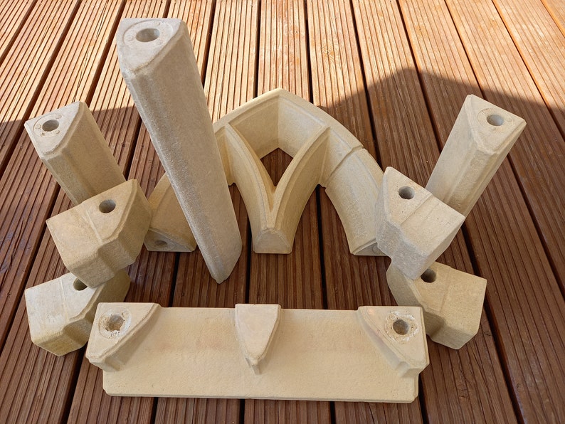 May include: A set of nine beige stone pieces that can be assembled to create a decorative archway. The pieces are made of a lightweight material and have a rough, textured surface.