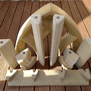 May include: A set of beige stone pieces that can be assembled to create a decorative archway. The pieces are designed to fit together to create a pointed arch shape.