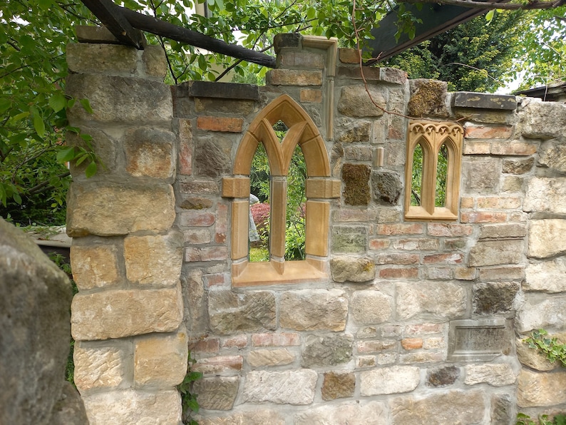 May include: A stone wall with two arched windows. The windows are made of a light brown stone and have a pointed arch. The wall is made of a variety of stones, including brown, gray, and white.