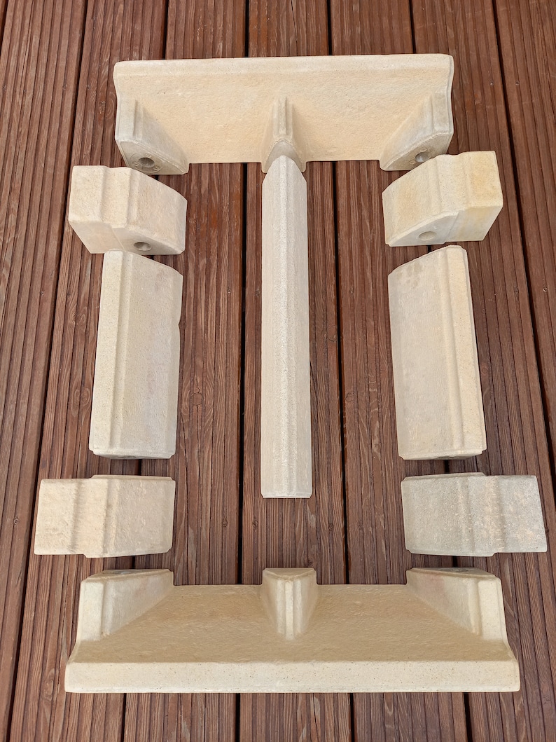 May include: A set of eight beige stone fireplace surround pieces. The pieces are shaped to create a rectangular opening for a fireplace.