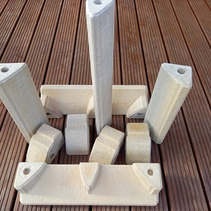 May include: A set of eight off-white ceramic building blocks with holes in the top. The blocks are arranged in a symmetrical pattern on a wooden surface.