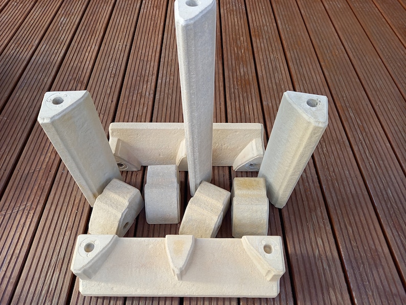 May include: A set of eight off-white ceramic building blocks with holes in the top. The blocks are arranged in a symmetrical pattern on a wooden surface.