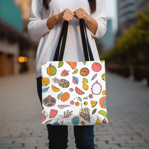 May include: A white tote bag with a colorful fruit pattern. The bag has black handles and features a variety of fruits including watermelon, pineapple, cherries, grapes, and pears.