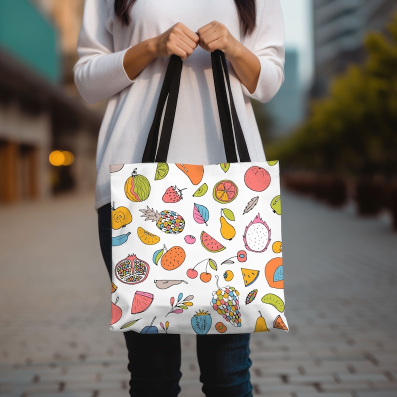 May include: A white tote bag with a colorful fruit pattern. The bag has black handles and features a variety of fruits including watermelon, pineapple, cherries, grapes, and pears.