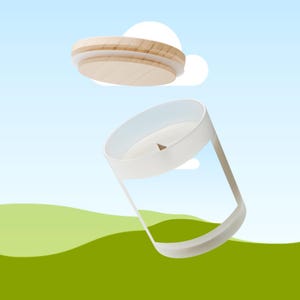 Peut inclure: Une bougie blanche dans un r&eacute;cipient en verre transparent avec un couvercle en bois. Le couvercle est en bois clair et poss&egrave;de un bord blanc. La bougie est plac&eacute;e sur un fond de ciel bleu et de collines vertes.