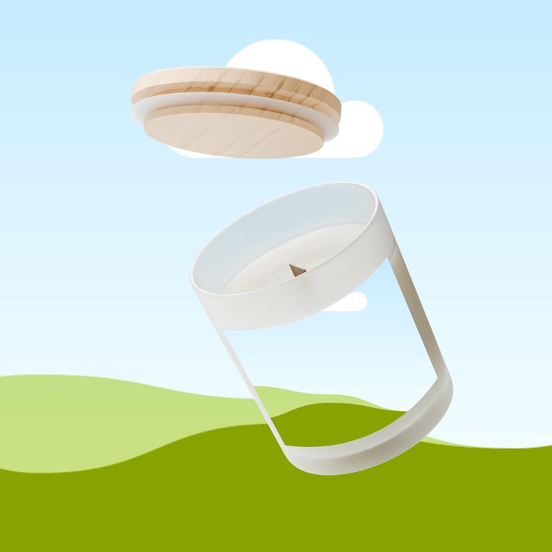 Peut inclure: Une bougie blanche dans un r&eacute;cipient en verre transparent avec un couvercle en bois. Le couvercle est en bois clair et poss&egrave;de un bord blanc. La bougie est plac&eacute;e sur un fond de ciel bleu et de collines vertes.