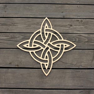 May include: A light-colored wooden Celtic knot symbol, featuring an intricate interwoven design. The symmetrical shape has four points, each with a leaf-like shape. The artwork is displayed against a backdrop of weathered, gray wooden planks.