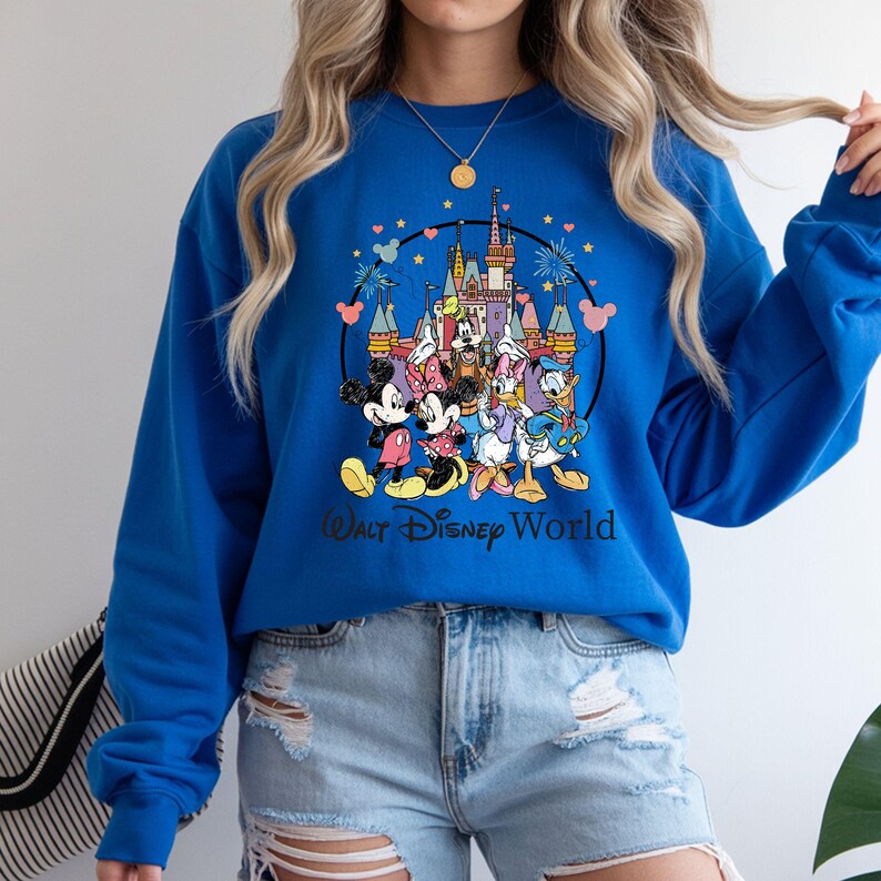 May include: Royal blue sweatshirt featuring a colorful graphic of Disney characters, including Mickey and Minnie Mouse, Donald and Daisy Duck, and the Disney World castle. The words "Walt Disney World" are printed below the graphic.