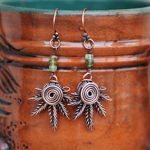 Könnte beinhalten: Ein Paar Ohrringe aus Kupferdraht mit grünen Edelsteinperlen und einem Spiraldesign. Die Ohrringe sind handgefertigt und haben einen rustikalen, böhmischen Stil.