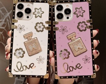 May include: Two phone cases with a black and gold frame. The cases have a pink and white background with a floral design and a rhinestone perfume bottle. The text "Love" is written on both cases.