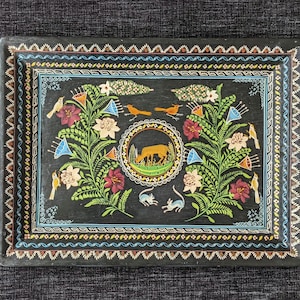 Könnte beinhalten: Ein rechteckiges schwarzes Tablett mit einem zentralen kreisförmigen Medaillon, das einen Hirsch zeigt, umgeben von symmetrischen Blumenmustern, grünem Blattwerk und verschiedenen Vögeln. Der Rand ist mit geometrischen Motiven verziert.