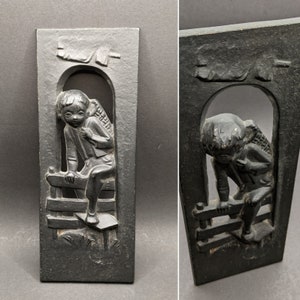 Austrian &#39;TRM&#39; Cast Iron Wall Plaque of Little Boy Carrying a Sack and Climbing a Fence, Vintage Metal Relief Wall Hanging by TRM.