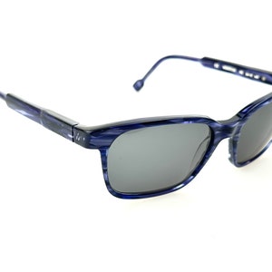 Puede incluir: Gafas de sol de plástico rayadas en azul y gris con montura rectangular.