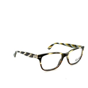 Puede incluir: Un par de gafas de pasta de carey con un patrón blanco y negro. Las gafas tienen una bisagra plateada y el nombre de la marca "Persol" está impreso en la lente derecha.