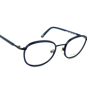 May include: Blue metal frame eyeglasses with round lenses. The frame has a black accent at the bridge.