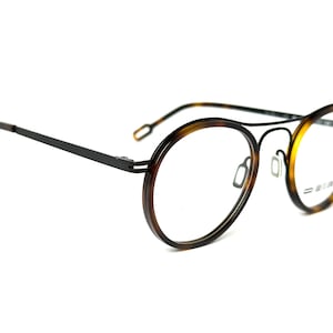 May include: Black metal frame eyeglasses with round tortoise shell lenses.