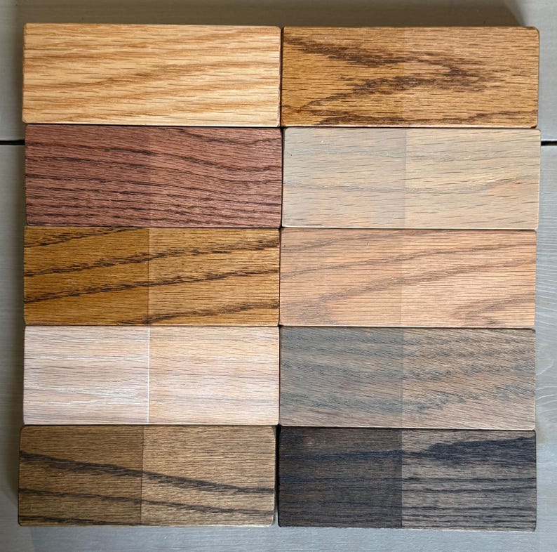 May include: Eight wood samples with different stains. Each sample is divided into two sections, one with a lighter stain and the other with a darker stain. The stains range from light brown to dark brown and black.