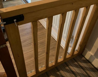 May include: A wooden gate with vertical slats, a black metal latch, and a white radiator in the background.