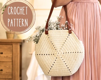 Puede incluir: Bolso de crochet color crema con asas de cuero marrón. El bolso tiene un diseño geométrico y está lleno de flores blancas. El texto "CROCHET PATTERN" está en un marco circular en la esquina superior izquierda.
