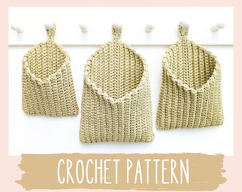 May include: Three crocheted hanging baskets in a light beige color, with a scalloped edge, hanging on a white wall with the text "CROCHET PATTERN" below.