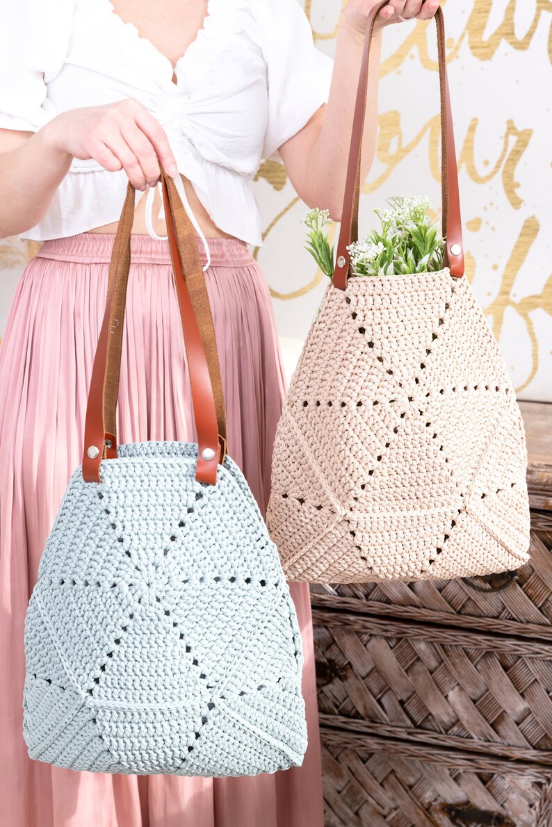Op de afbeelding: Twee gehaakte tassen met leren handvatten. De tas links is lichtblauw en de tas rechts is beige.