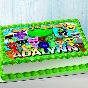 Può includere: Una torta di compleanno rettangolare con glassa verde e base bianca. La torta è decorata con personaggi dei cartoni animati e la scritta "HAPPY 7TH BIRTHDAY ADALYNN". La torta ha un bordo verde.