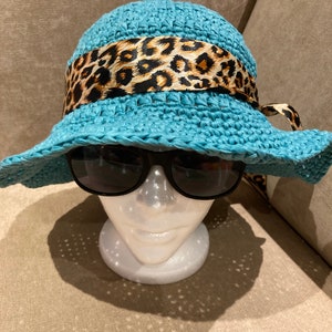 May include: A light blue sun hat with a leopard print ribbon. The hat is on a mannequin head.
