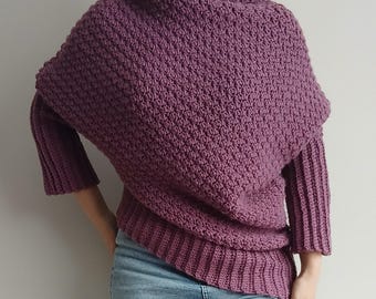 May include: A mauve-colored, long-sleeved knit sweater featuring a textured, bobble-like stitch pattern on the body, a high ribbed collar, and ribbed cuffs and hem. The garment is paired with light blue denim jeans, creating a casual ensemble.