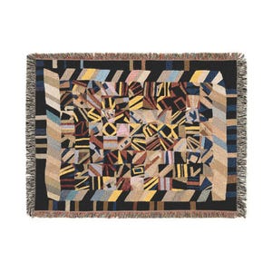 May include: Woven throw blanket with a geometric pattern in shades of black, beige, yellow, blue, and brown. The blanket has a fringed edge and a repeating design of abstract shapes. The overall design is a patchwork style.