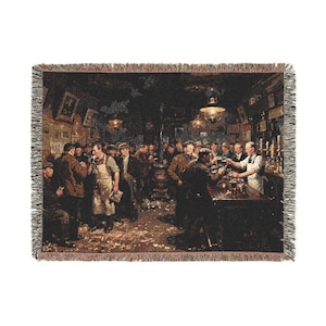 May include: A rectangular woven throw blanket featuring a detailed tapestry scene of a crowded 19th-century pub interior. The image depicts numerous figures in dark clothing, a bartender, and a central stove, finished with a fringed edge.