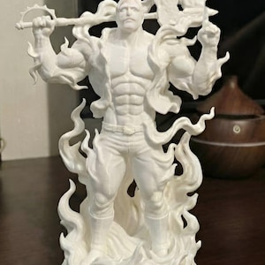 May include: A white figurine of a muscular male figure holding a weapon with a crescent-shaped blade. The figure is surrounded by stylized flames. The statue is standing on a circular base.