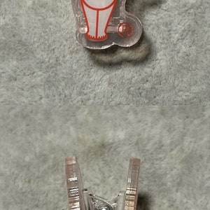 Pu&ograve; includere: Clip in plastica trasparente con un disegno di un bambino dei cartoni animati con contorni rossi. Il bambino ha le braccia tese e sorride. La clip &egrave; mostrata da due angolazioni, dall'alto e di lato.